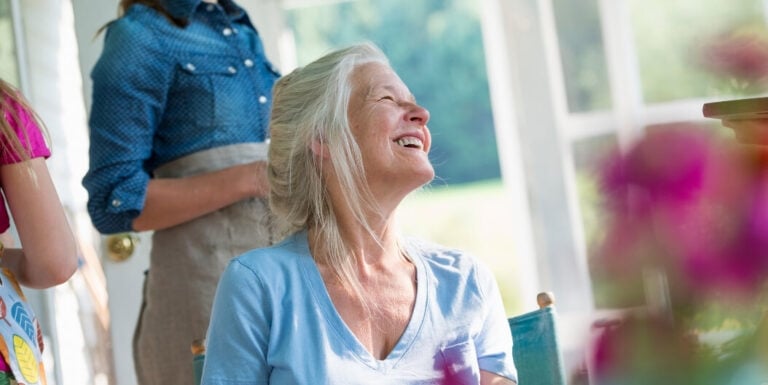 Elderly Woman Laughing Freely on Sunny Porch at Assisted Living Facility